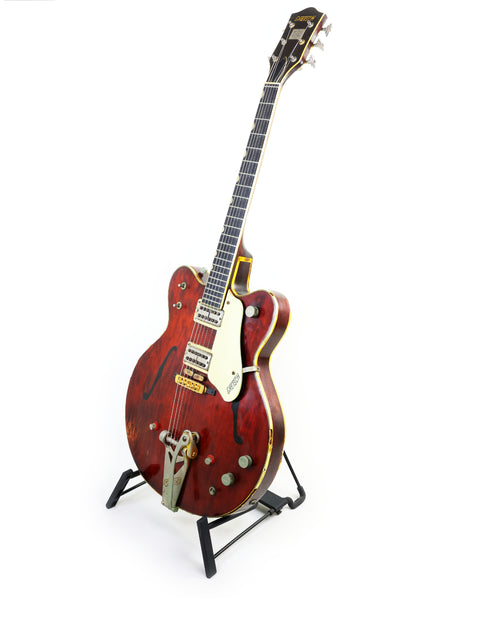 Classic 1964 Gretsch 6122 Country Gentleman guitar in vibrant red, displayed elegantly on a stand against a white backdrop.
