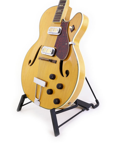 Classic Harmony H71 Meteor guitar displayed on a stand, highlighting its vintage charm with a crisp white backdrop.
