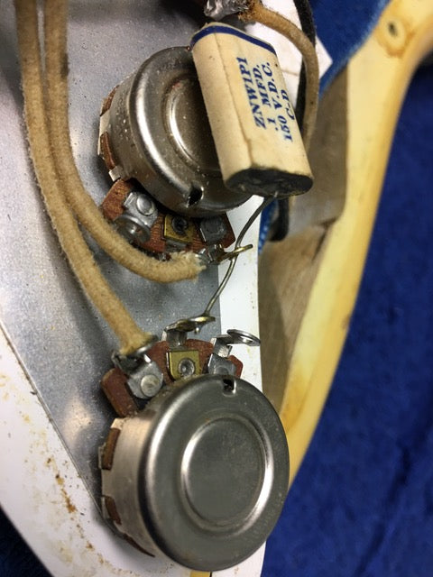 Close-up image of a vintage 1959 Fender Stratocaster, focusing on the pickup and wire, with a blond finish and maple neck.
