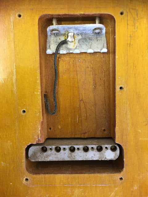 Close-up image of a wooden box with a metal hook, highlighting a vintage 1958 USA Fender Stratocaster.
