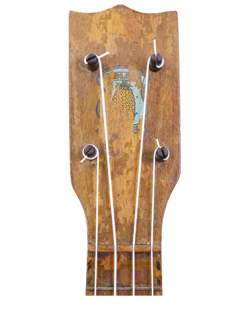 Close-up of a 1930 Kamaka Pineapple Ukulele, highlighting its wooden head and neck, a symbol of vintage Hawaiian music.
