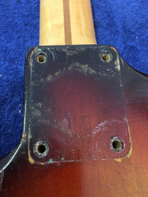 Close-up of a 1958 Fender Stratocaster neck featuring a prominent hole, highlighting its vintage wear.
