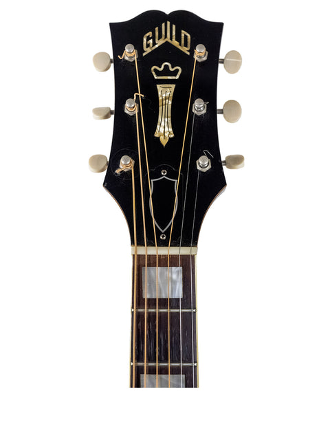 Close-up of a 1962 Guild F-40 Valencia guitar headstock with a prominent gold logo, highlighting its vintage appeal.