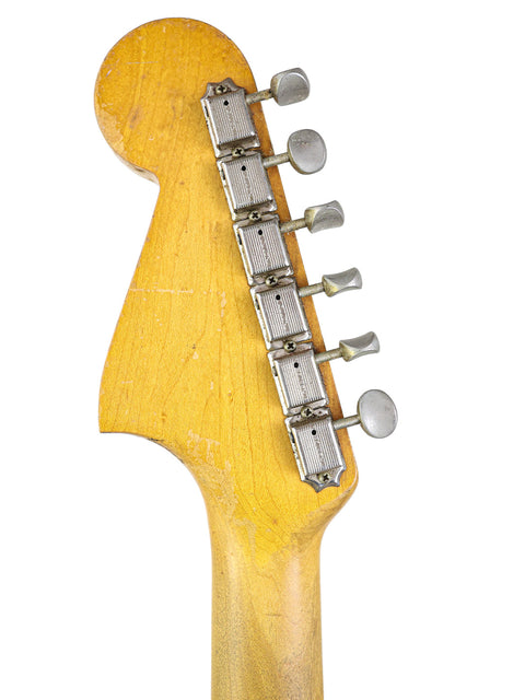 Close-up of a 1964 Fender Jaguar guitar neck, highlighting its vintage finish and intricate details.
