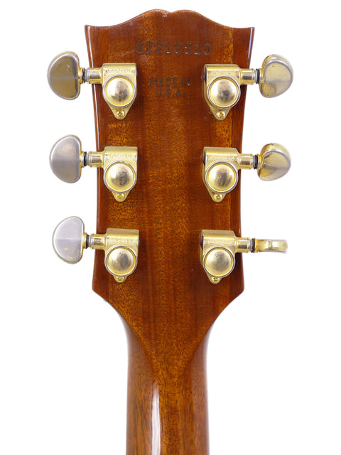 Close-up of a 1994 Gibson Les Paul Custom headstock with shiny brass knobs for tuning.