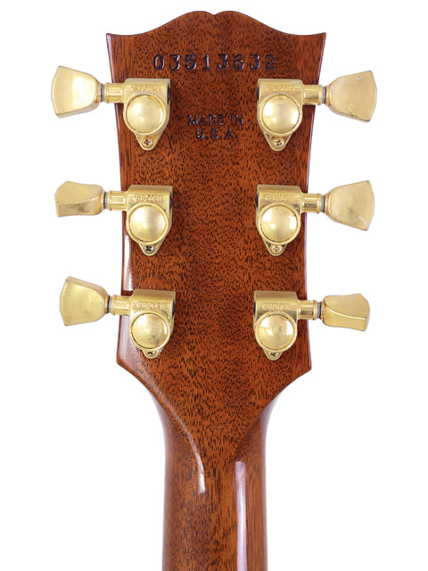Close-up of a 2003 Gibson Les Paul Supreme headstock showcasing its luxurious gold hardware.