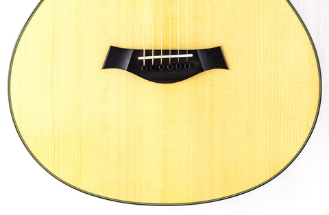 Close-up of a 2011 Taylor Custom GS Baritone 6 guitar, with a black pick positioned on its body, ready to play.