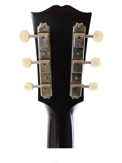 Close-up of a Gibson J-45 True Vintage headstock from 2012, highlighting four knobs that control its electric sound.