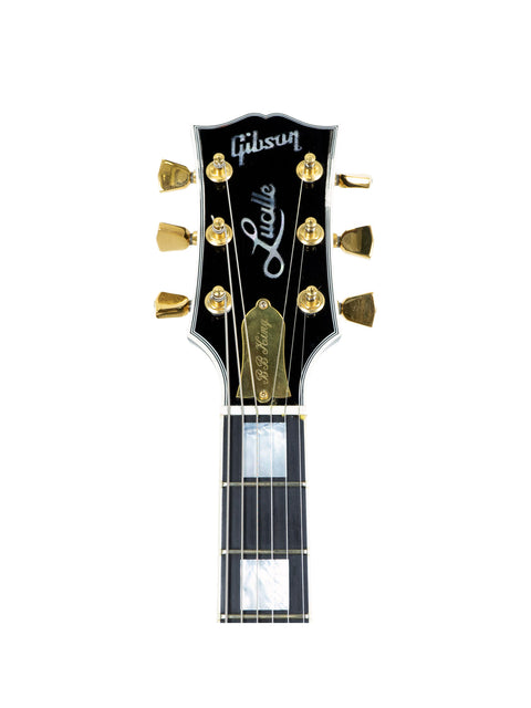 Close-up of a guitar head featuring gold hardware, signed by BB King and Eric Clapton, showcasing its unique craftsmanship.