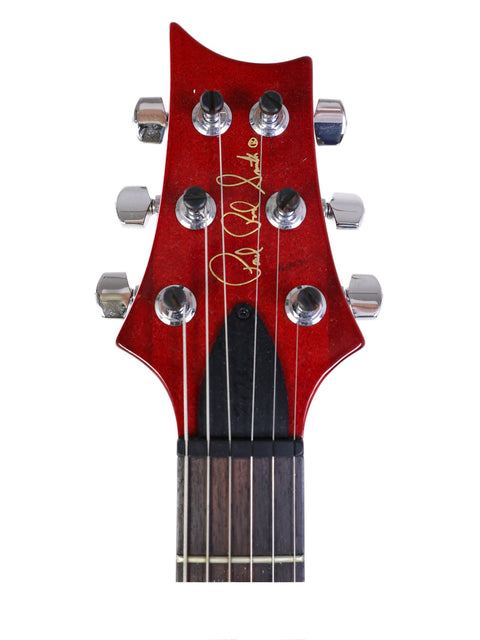 Close-up of a red guitar headstock featuring a black pickguard, identified as a 2005 PRS Custom 22 from the USA.