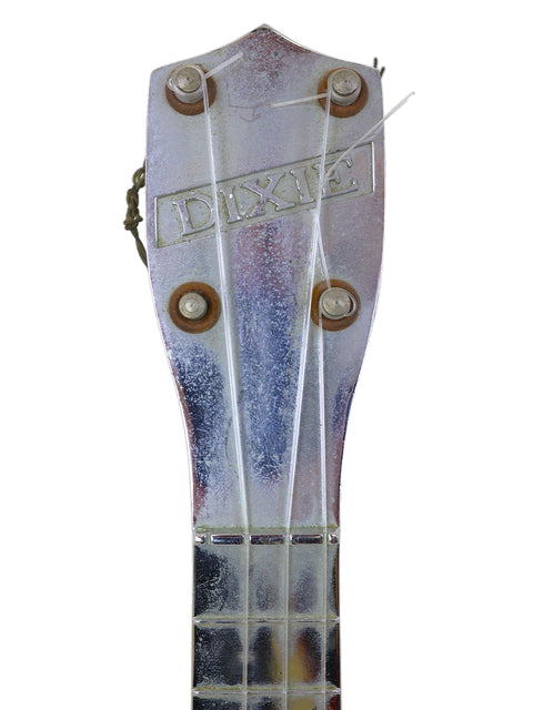 Close-up of a rusty guitar headstock with the word "DIXIE" etched into it.
