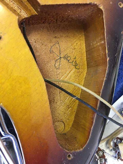 Close-up of a vintage 1958 Fender Stratocaster guitar with a guitar pick placed in the neck, emphasizing its iconic style.
