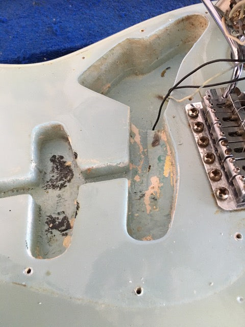 Close-up of a vintage Fender Stratocaster guitar with a broken neck, showcasing its unique refinishing from 1972.