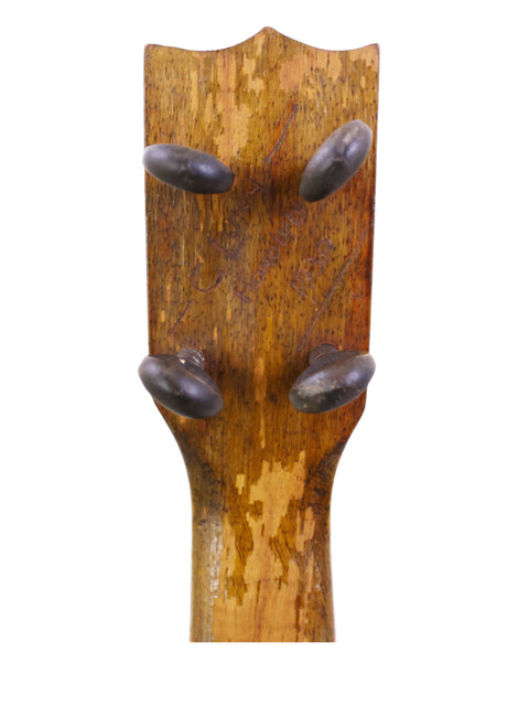 Close-up of a vintage Kamaka Pineapple Ukulele head, showcasing intricate wood grain and classic design from 1930s Hawaii.