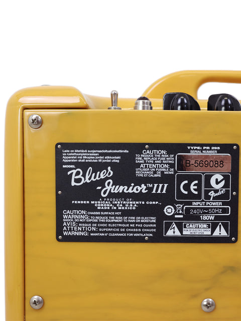 Close-up of a yellow guitar amplifier with labels and knobs, model "Blues Junior III".