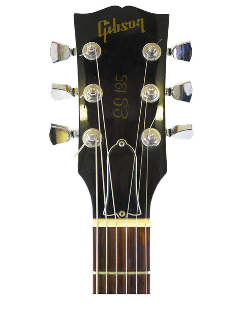 Close-up of the headstock from a 2001 Gibson ES-135 acoustic guitar, set against a stark white background for emphasis.