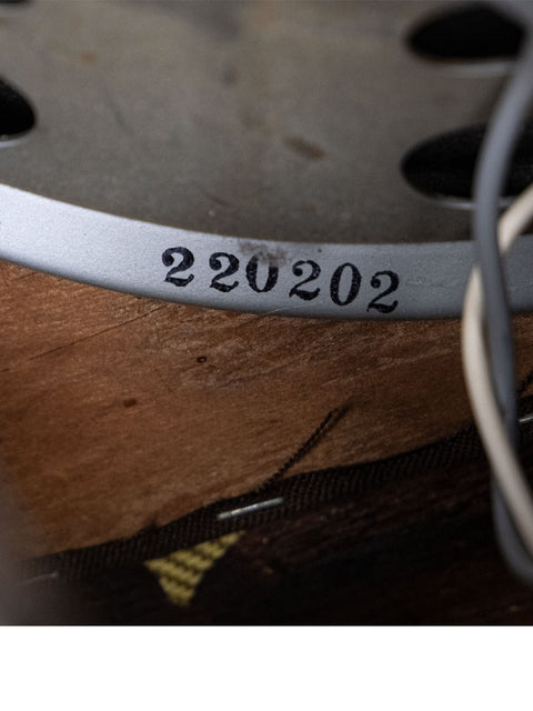 Close-up shot of a metal plate featuring the number 2023, linked to a 1952 Fender Tweed 5B3 Deluxe model.