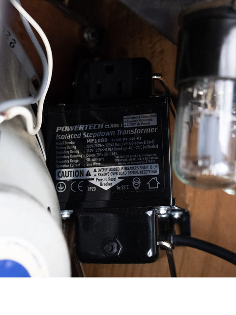 Detailed view of a 1952 Fender Tweed 5B3 Deluxe power supply alongside a light bulb, highlighting vintage aesthetics.
