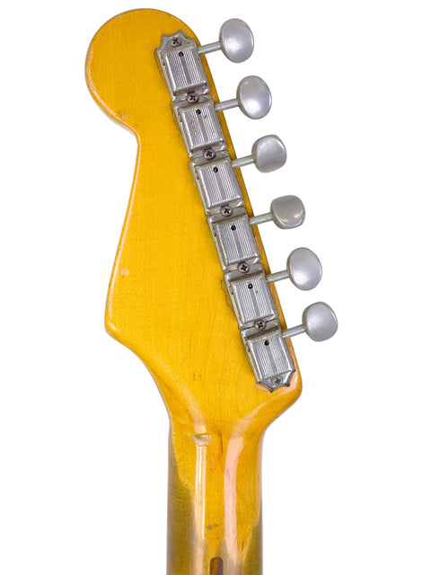 Detailed view of a 1954 Fender Stratocaster guitar head, featuring a vibrant yellow body, highlighting its vintage appeal.