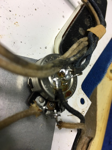 Detailed view of a 1959 Fender Stratocaster guitar, showcasing wires and a switch on its blond maple neck.
