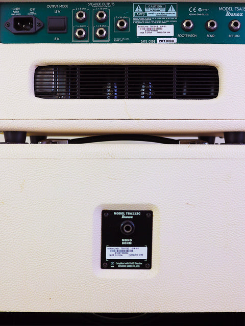 Detailed view of a white Ibanez TSA15 Tube Screamer amplifier and remote control, highlighting the equipment's modern features.