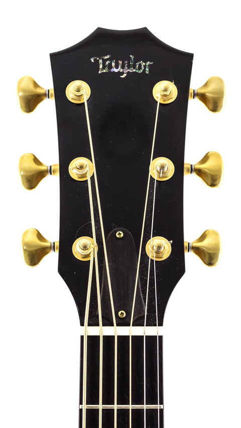 Detailed view of the headstock on a 2011 Taylor Custom GS Baritone 6 guitar, highlighting its stunning gold hardware.
