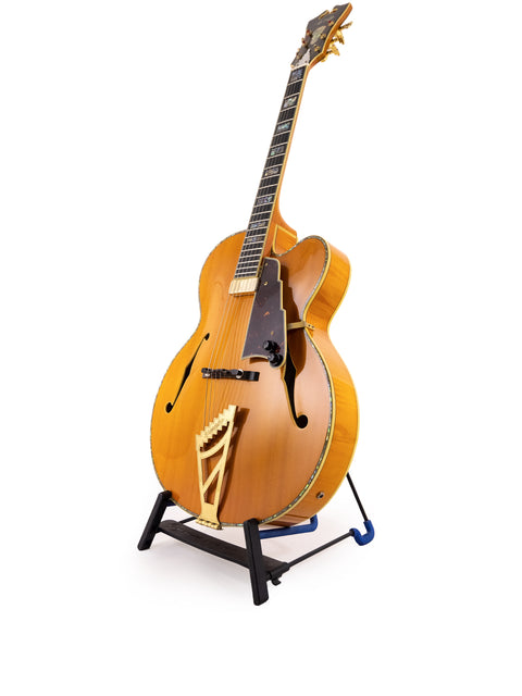 Displayed on a stand, the D’Angelico New Yorker Series Excel EXL-1DP guitar contrasts beautifully with the white background.