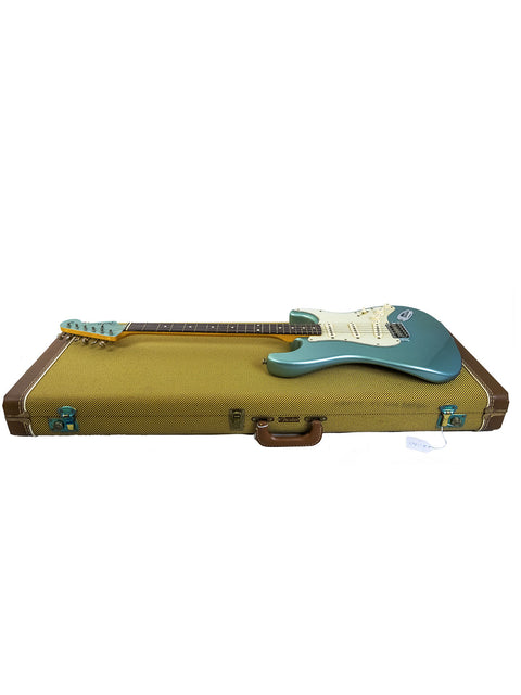 Electric guitar with teal body in an open brown case.