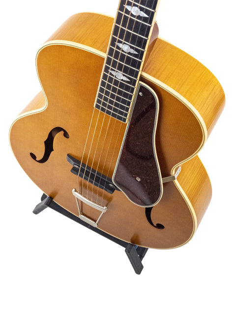 Epiphone Masterbilt De Luxe F-Hole Archtop guitar from 2016 displayed on a stand with a white backdrop.

