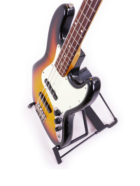 Fender Custom Shop '64 Jazz Bass Relic elegantly positioned on a stand with a bright white background.