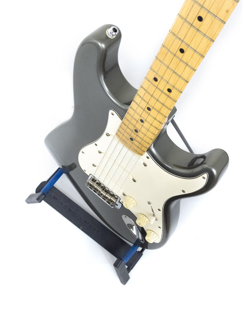 Fender Eric Clapton Signature Series Stratocaster from 1988, featuring a sleek black body and vibrant blue pick guard.
