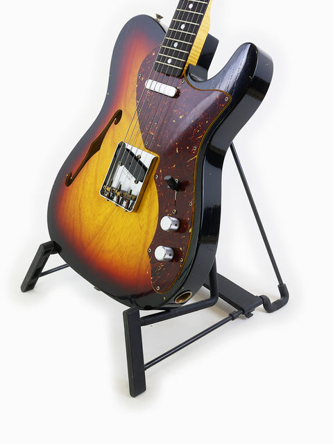 Fender Limited Edition ’60s Telecaster Thinline Journeyman Relic guitar with a sunburst finish, elegantly placed on a stand.