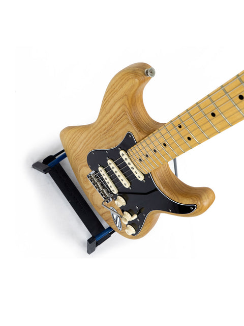 Fender Stratocaster featuring a wooden body and black pick guard, highlighting its natural oiled ash design from 2015.
