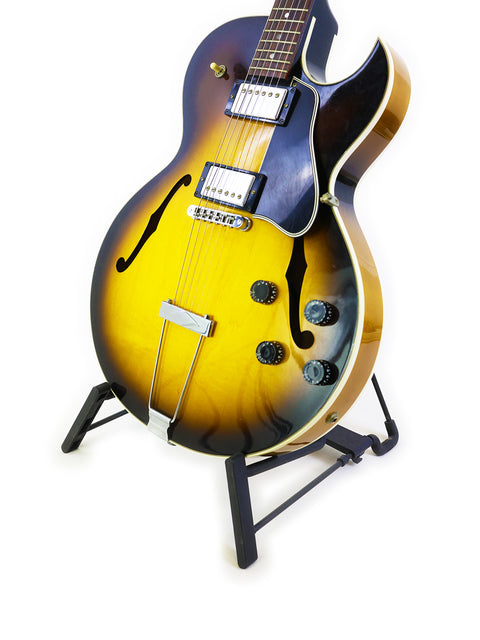 Gibson ES-135 guitar with a yellow sunburst finish displayed on a stand, showcasing its elegant design and craftsmanship.