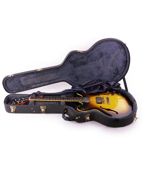 Gibson ES-335 Nashville guitar from 2006, nestled in a case on a white background, emphasizing its sleek and iconic shape.