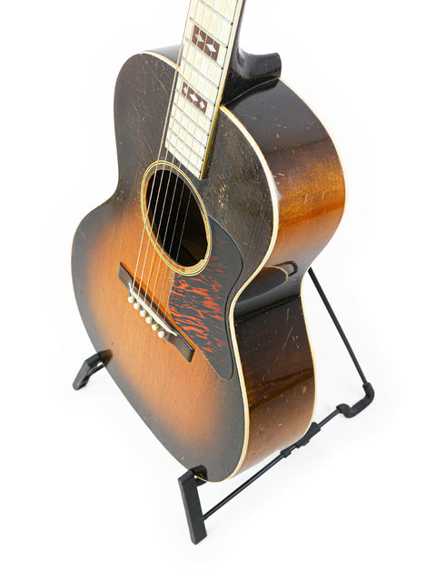Gibson L-C 'Century of Progress' guitar on a stand against a clean white background, showcasing its vintage design.