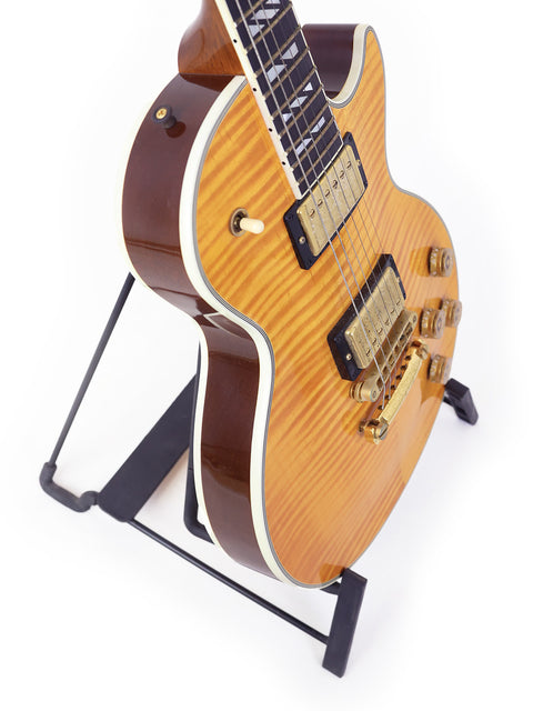 Gibson Les Paul Supreme guitar from 2003 resting on a stand, with a minimalist white background emphasizing its craftsmanship.

