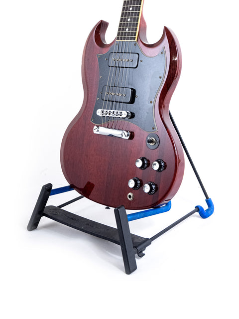 Gibson SG Classic guitar on a stand, showcasing its sleek design against a clean white background. Perfect for musicians.