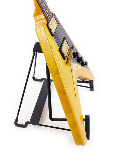 Ibanez 2387CT Rocket Roll Sr. Flying V guitar in yellow on a stand, adorned with a black strap, from Japan, 1976-77.