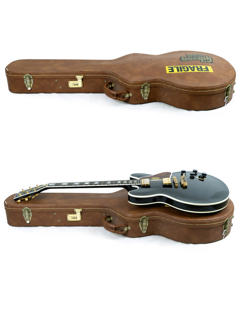 Inside a case, a black Gibson Lucille signed by BB King and Eric Clapton rests alongside a brown guitar, ready for play.