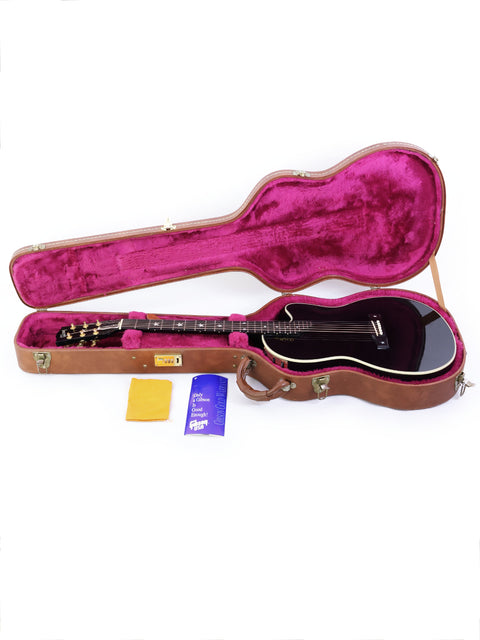 Inside a guitar case, a black Gibson Chet Atkins SST from 1998 is displayed, highlighting its elegant shape and finish.
