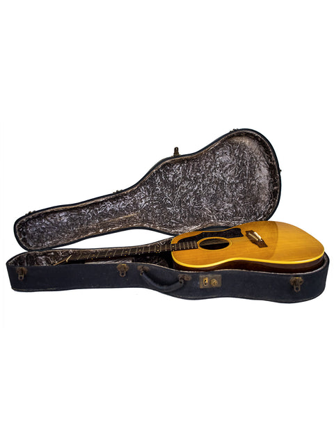 Inside a guitar case, a yellow 1962 Gibson LG-3 Acoustic guitar rests, representing vintage craftsmanship.