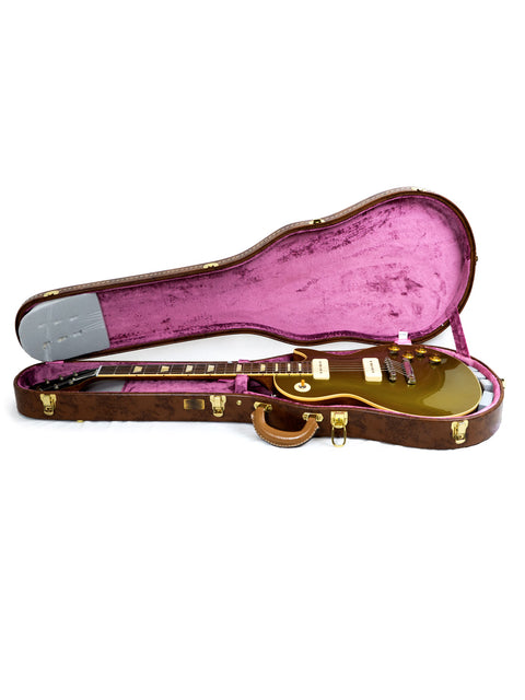 Inside a guitar case lies a gleaming gold Gibson Les Paul Reissue, highlighting its exquisite design and limited edition status.