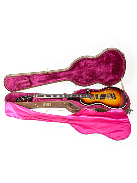 Inside a pink-covered guitar case lies a 1997 Gibson Nighthawk, highlighting its classic shape and style.
