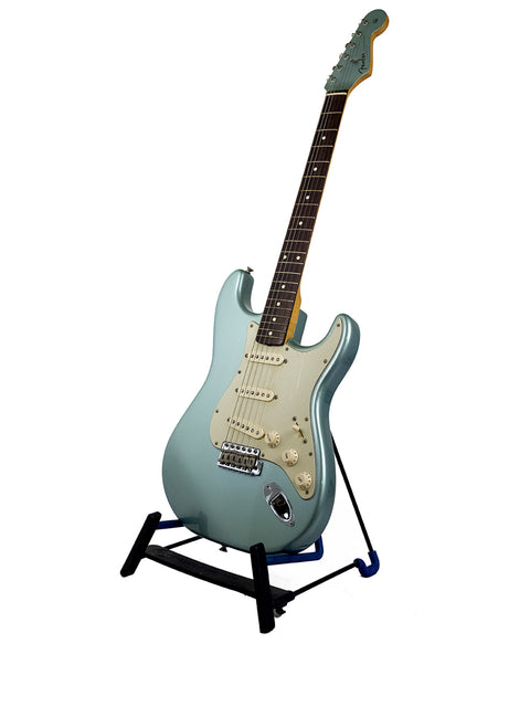 Light blue electric guitar on a black stand with a white background.