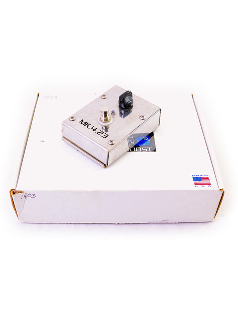 Metal foot switch on a white cardboard box against a white background.
