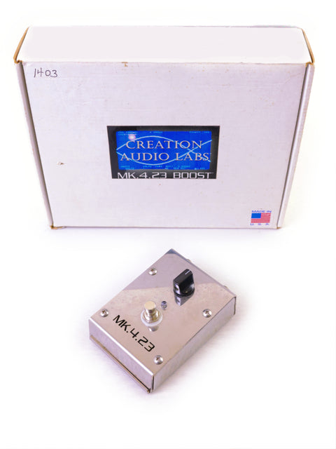 Metal guitar pedal labeled "MK.4.23 BOOST" in front of its packaging box.