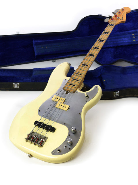 On the floor, a white Ibanez Silver Series P/J bass guitar from 1978 is nestled in its case, reflecting its timeless appeal.