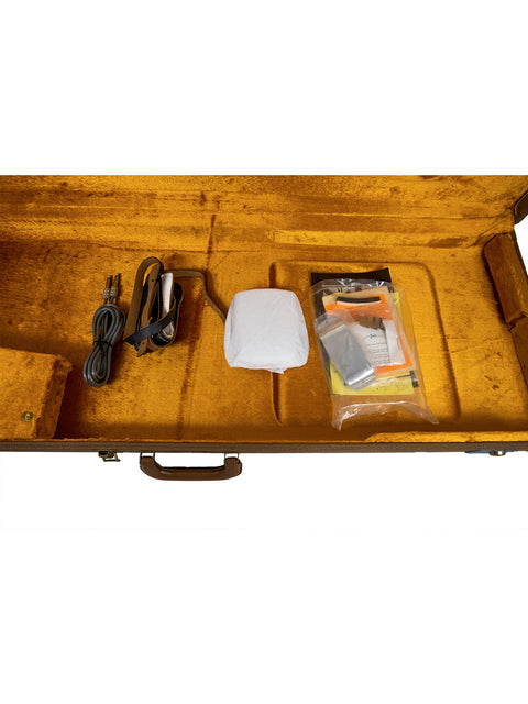 Open brown case with a power cord, white object, and clear plastic bag with items inside.