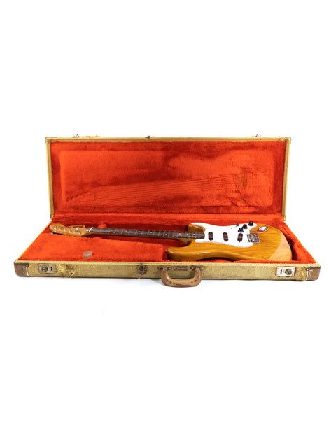 Orange case holding a vintage 1979 Fender Stratocaster guitar, displayed on a white surface.